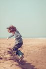 Garçon jouer et sauter sur la plage — Photo de stock