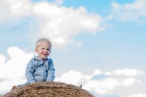 Мальчик сидит на тюке сена — стоковое фото