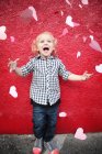 Boy throwing paper hearts in air — Stock Photo