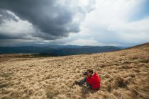 Человек сидит на сухой траве и фотографирует — стоковое фото