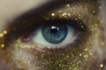 Ojo de mujer con purpurina de oro - foto de stock