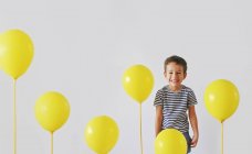 Niño riendo con globos amarillos - foto de stock