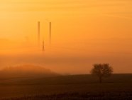 Schornsteine eines Kraftwerks im orangen Nebel — Stockfoto