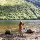Chica lanzando piedras en el lago - foto de stock