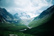 Vallée au pied des montagnes enneigées — Photo de stock