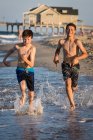 Dos chicos corriendo en la playa - foto de stock
