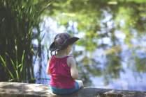 Menina sentada à beira do lago — Fotografia de Stock
