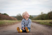 Carefree menino sentado no caminho — Fotografia de Stock