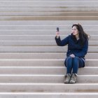 Жінка фотографується на мобільному телефоні — стокове фото