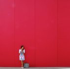 Mulher em pé na frente da parede vermelha — Fotografia de Stock