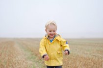 Menino no campo em roupas de chuva — Fotografia de Stock