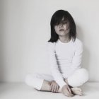 Menina sentado de pernas cruzadas com os olhos fechados — Fotografia de Stock