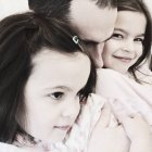 Pai e duas filhas abraçando — Fotografia de Stock