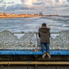 Ragazzo guardando spiaggia sul molo — Foto stock