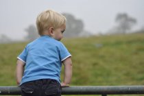 Boy leaning over fence — Stock Photo