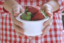 Tazón de manos con fresas - foto de stock