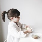 Chica comiendo kiwi en la mesa - foto de stock