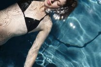Mujer flota en la piscina - foto de stock