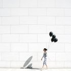 Frau läuft mit schwarzen Luftballons — Stockfoto