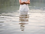 Дівчина в одязі, стоячи в озері — стокове фото