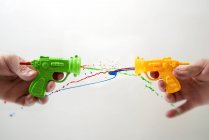 Pistolas de brinquedo atirando tinta colorida — Fotografia de Stock
