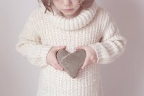 Girl holding heart shaped stone — Stock Photo