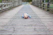 Niño acostado en el puente - foto de stock