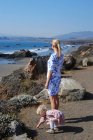 Madre e hija de pie en la playa - foto de stock