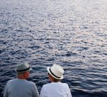 Пара з капелюхами дивиться на море — стокове фото