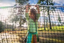Girl on tennis court lifting net — Stock Photo