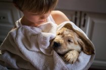 Хлопчик обіймає вологого цуценя собаку — стокове фото