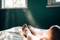 Rayos de sol matutinos en piernas femeninas - foto de stock