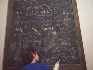 Boy writing on blackboard — Stock Photo