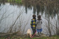 Children and puppy standing at water — Stock Photo
