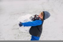 Boy carrying large snowball — Stock Photo