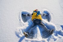 Ragazzo che fa un angelo di neve — Foto stock