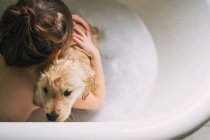 Garçon prenant un bain avec chien chiot — Photo de stock