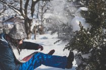 Girl kicking snow off tree — Stock Photo