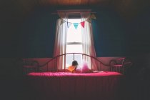 Дівчина в ліжку дивиться з вікна — стокове фото