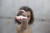 Chica sosteniendo la burbuja de jabón en la mano - foto de stock