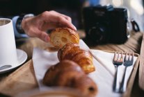 Hand reaching for croissant — Stock Photo