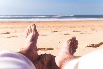 Jambes masculines sur la plage de sable — Photo de stock