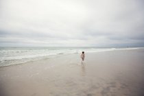 Boy running away along beach — Stock Photo