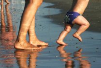 Donna e bambino camminano sulla spiaggia — Foto stock