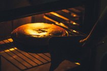 Human hand placing pie in oven — Stock Photo