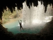 Woman jumping into waterfall — Stock Photo