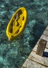 Yellow canoe tied to wooden pier — Stock Photo