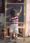 Boy writing on blackboard — Stock Photo