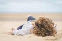 Menino deitado na praia — Fotografia de Stock