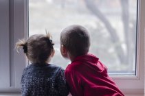 Niño y niñas mirando por la ventana - foto de stock